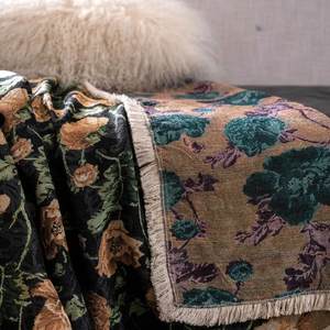 Detail of floral jacquard woven sofa throw with vintage flower patterns and fringe edge