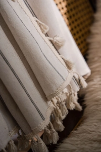 Detail von beigem gestreiftem Vorhang mit eleganten Fransen und gewebter Leinen-Textur
