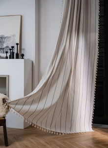 Detail eines Vorhangs im Boho-Stil aus cremefarbener Baumwolle mit schwarzen Streifen
