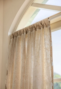 Detailed view of daisy print curtain fabric with delicate white lace border finish