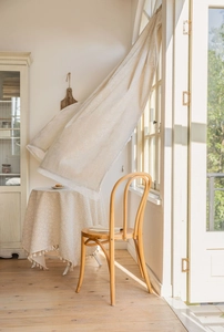 Detail of light beige lace curtains with floral embroidery and tassel fringe in sunlight