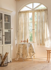 Detail of grey floral print beige curtains and matching tablecloth in rustic style