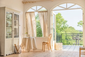 Detailed view of light beige lace curtains and matching tablecloth with floral embroidery
