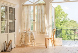 Detailed view of floral blue print curtains and matching tablecloth in rustic French style