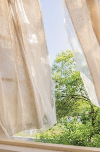 Detail of beige lace curtain with daisy floral pattern in rustic French crochet style