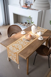Detailed close-up of yellow jacquard table runner with vintage floral patterns and tassels