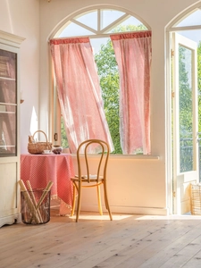 Detail of red and white checkered curtains featuring delicate lace edges in a rustic kitchen