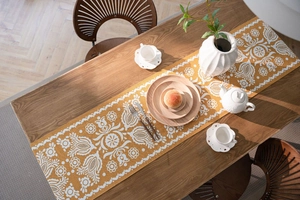 Macro detail of mustard yellow jacquard table runner with white ethnic floral patterns