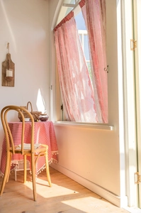 Detail of red gingham curtains featuring white lace edges and matching tassel tablecloth