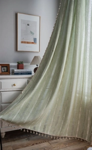 Détail d'un rideau en lin vert avec rayures brodées blanches et bordure à pompons élégante