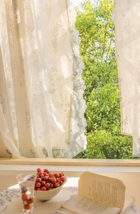 Detailed close-up of cream lace curtain with floral embroidery and wavy scalloped edges
