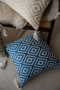 Detail shot of boho woven pillow cover with geometric pattern and creamy white tassels