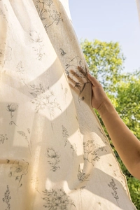 Detail of floral sketch print on semi-sheer linen fabric curtains in natural outdoor light