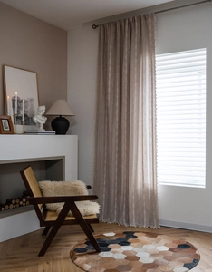 Close-up of beige linen curtain with white stripes and elegant tassels on the edge