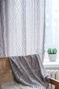 Detail of light purple lace curtain with geometric patterns and fringe for windows