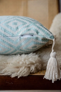 Detail of mint green jacquard pillowcase with hidden zipper and beige tassel accents