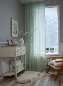 Detailed view of light green crochet lace curtain with floral patterns and tassel edges