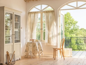 Detail of elegant white lace curtain with delicate floral patterns in a French country room