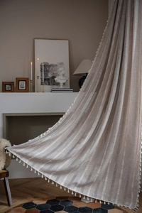 Close-up of beige semi-sheer curtain with white wave jacquard and decorative tassel fringe