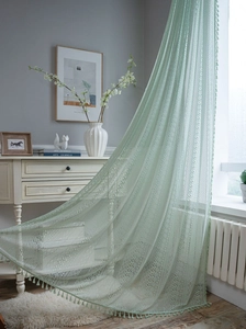 Detail of light green lace curtain featuring crochet hollow patterns and fringe trim
