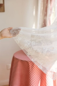 Close-up of white floral lace embroidery fabric with delicate mesh details for curtains