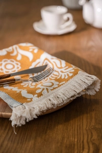 Detailed texture of jacquard table runner with yellow floral patterns and beige tassels