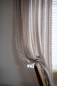 Detail of bohemian semi-sheer curtain with vertical stripes and delicate tassel fringe edge