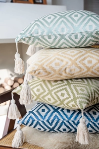 Detail of geometric diamond textured pillow covers with decorative off-white tassels