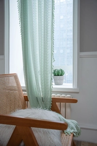 Detail view of mint green crochet lace curtain featuring hollow floral patterns and fringe