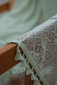 Macro detail of green crochet curtain featuring geometric lace patterns and tassel trim