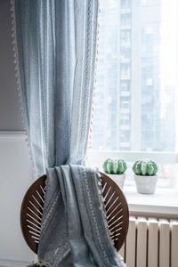 Detailed close-up of blue-grey striped linen curtain with elegant fringe edge details