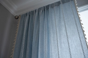 Dettaglio dei ricami a righe e nappe sui tendaggi della cucina in blu-grigio testurizzato