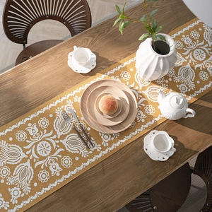 Ginger yellow jacquard table runner with vintage floral patterns on wooden table