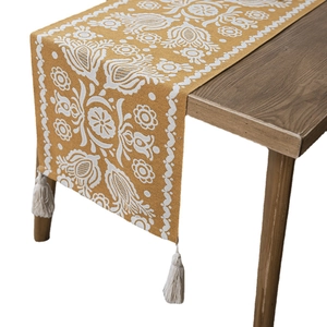 Mustard yellow jacquard table runner with white floral patterns and cream tassels