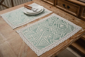 Close-up of bohemian placemat with mint green geometry and white lace edges