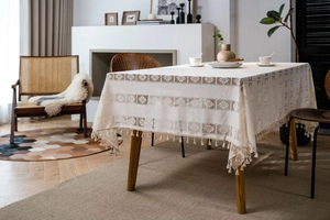 Close-up of cream rectangular crochet lace tablecloth with geometric patterns and fringe