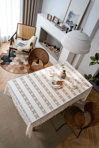 Detail of crochet hollow tablecloth with tassels in cream and light brown tones
