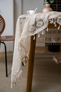 Detailed view of cream crochet lace tablecloth with elegant fringe tassels and hollow patterns