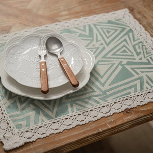 Modern green geometric table runner with tassels and lace on dark wood table