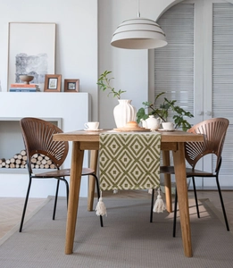 Close-up of bohemian woven table runner featuring green geometric patterns and tassels