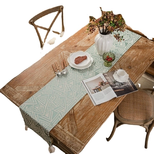 Modern geometric table runner with blue-green triangles and white fringe on wood