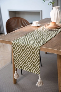 Detail of Nordic geometric green table runner with elegant fringe on a wooden table