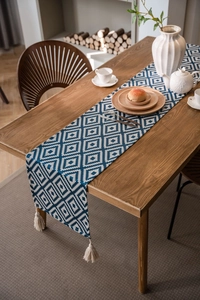 Detailed view of bohemian blue diamond pattern table runner with creamy white tassels