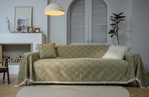 Detail of green geometric jacquard sofa cover with fringe edges and matching pillow