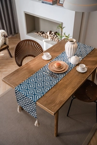 Detailed close-up of blue geometric jacquard table runner with handmade cotton tassels