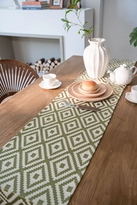 Detail of green and white geometric diamond table runner on dark wood dining table