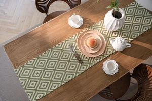 Close-up of green and white geometric jacquard table runner on a wooden dining table