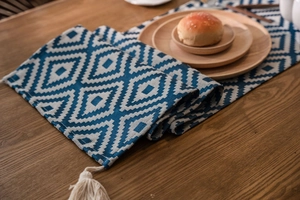 Detailed view of dark blue geometric jacquard table runner with beige woven tassels