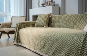 Close-up of green geometric jacquard sofa cover with fringe details and thick texture
