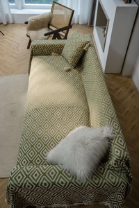 Close-up of green geometric jacquard sofa cover with fringe details and matching pillow